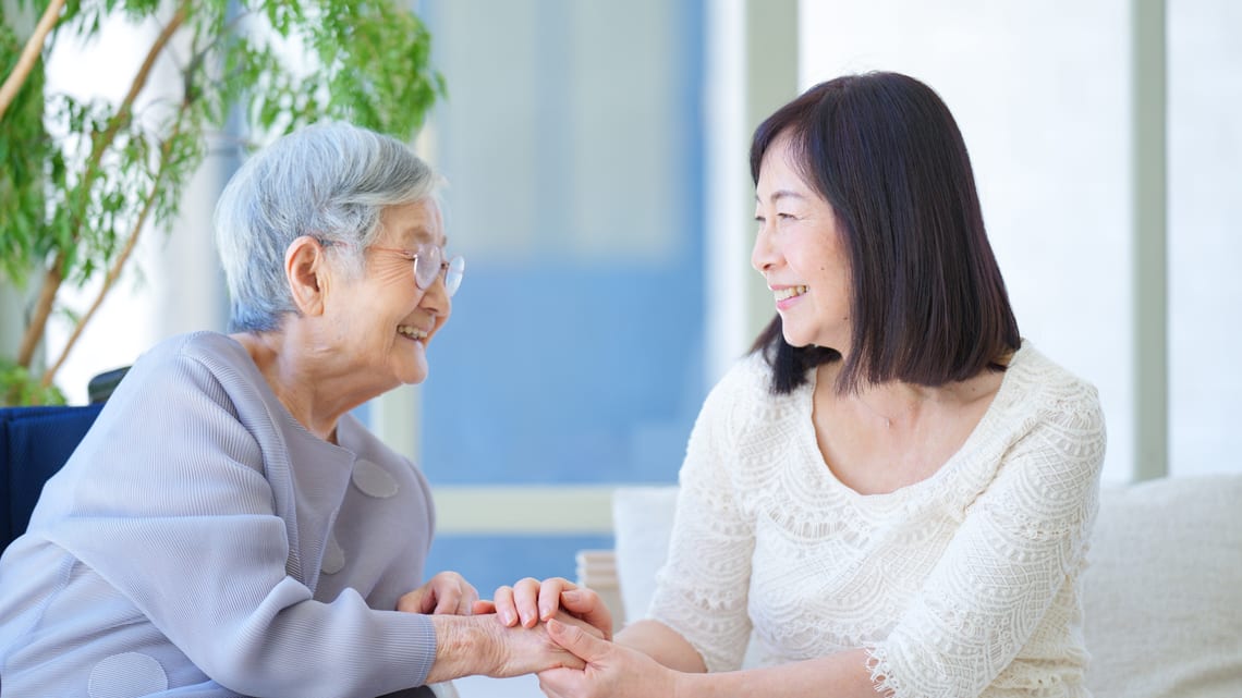 お母様の手を握り、笑顔で話す娘さんのイメージ