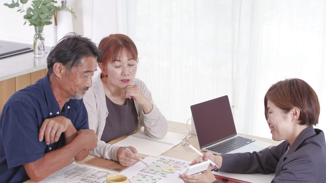 職員から書類を見ながら説明を受けるご夫婦のイメージ