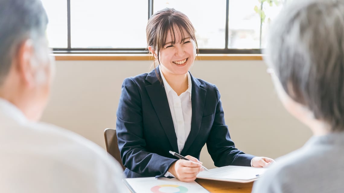 笑顔で相談に乗るケアマネジャーと、話を聞く高齢のご夫婦のイメージ