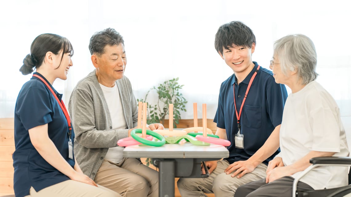 デイサービスで、介護職員と高齢の方がテーブルを囲んで話しているイメージ