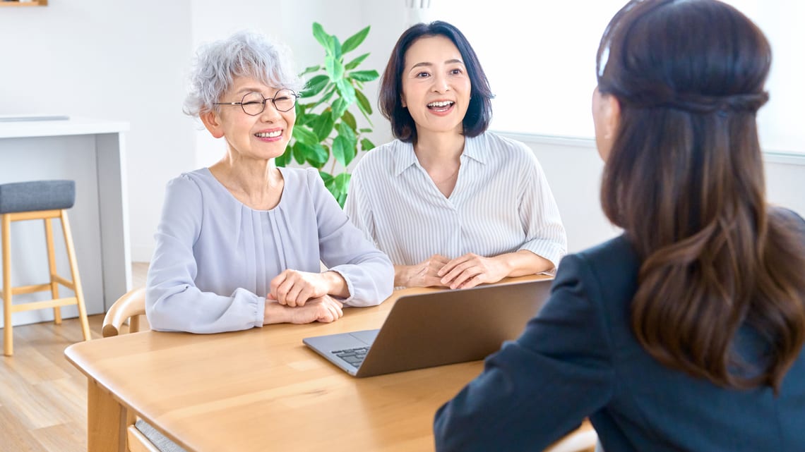 笑顔のお母様と娘さんが、テーブルで相談員と話しているイメージ