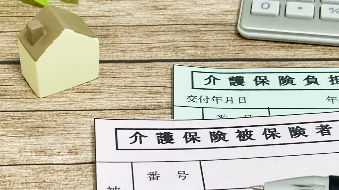 介護保険の書類と家の模型のイメージ
