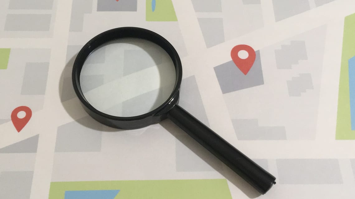 地図の上に、虫めがねと場所の印を置いたイメージ