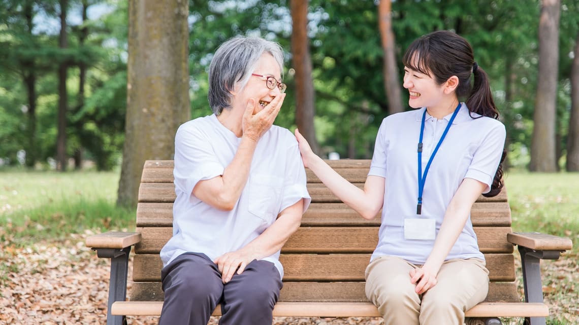 公園のベンチで介護スタッフと話す高齢の方のイメージ