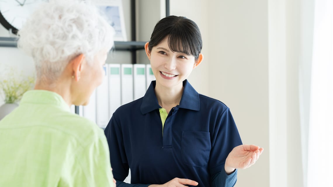 職員から説明を受けるシニアの女性のイメージ