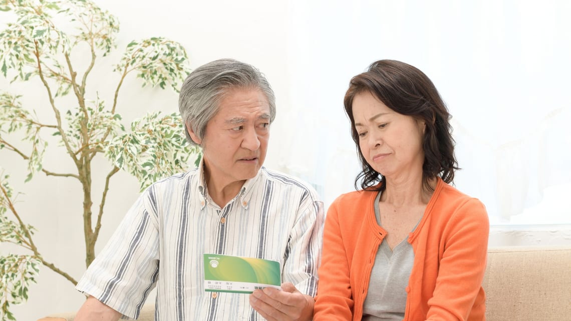 通帳を見ながら、毎月の費用を確かめる高齢のご夫婦のイメージ