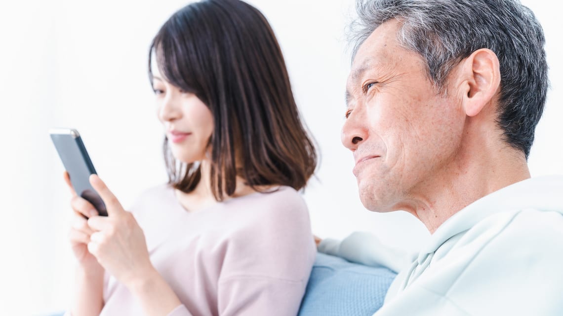 スマートフォンを見ながら、これからの住まいを話し合う父と娘のイメージ