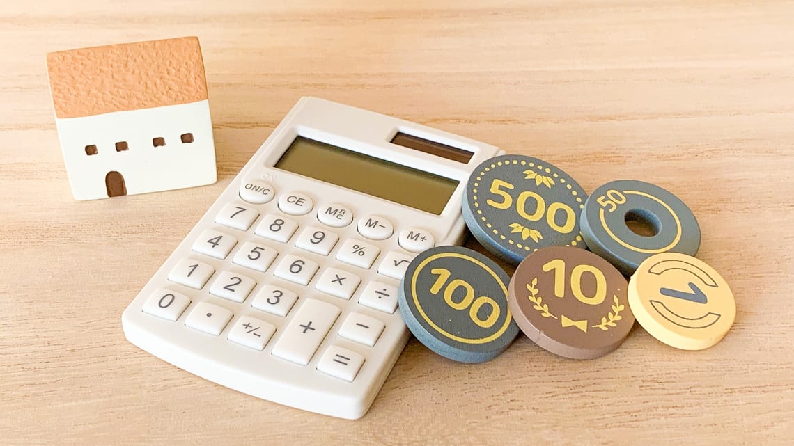 家の模型と電卓と硬貨のイメージ