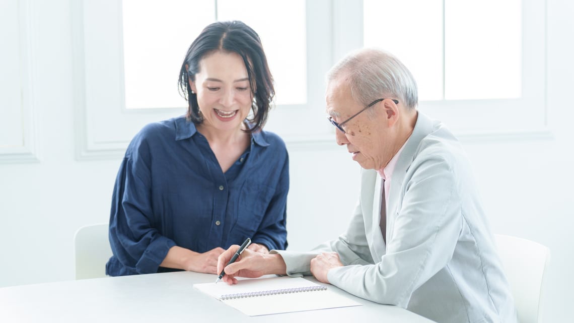 ノートに書き込むお父様と、そばで笑顔で話す娘さんのイメージ