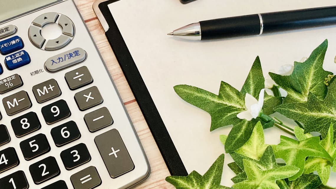 電卓とクリップボードと植物のイメージ
