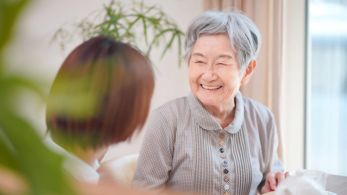 ご自宅に訪問したヘルパーと、笑顔で話す高齢の女性のイメージ