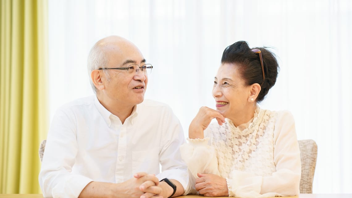 リビングで、笑顔で話す高齢のご夫婦のイメージ