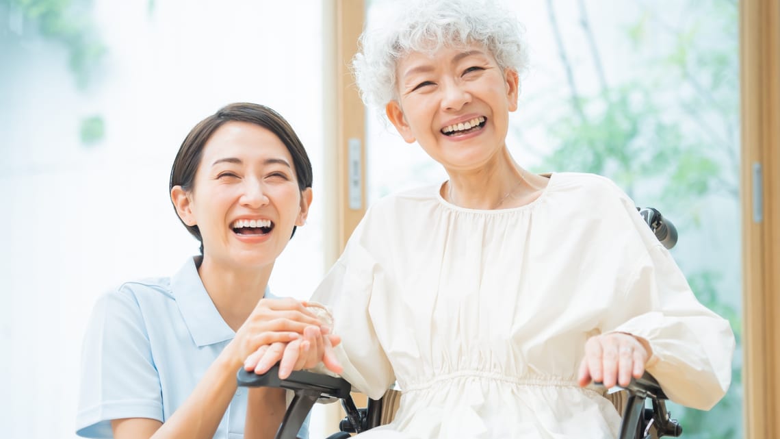 職員と笑顔で話す、車いすの高齢の女性のイメージ