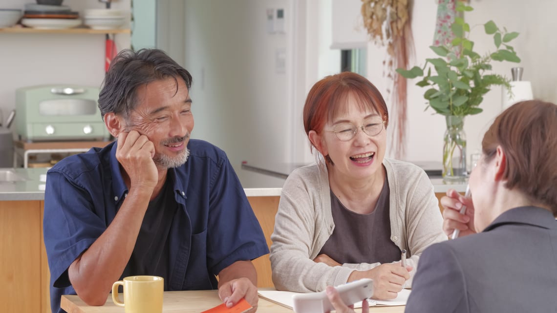 相談員から説明を受けながら、笑顔で話すご夫婦のイメージ